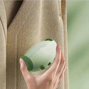 Hand using a lint roller on a beige coat fabric, showcasing ergonomic design and portability.