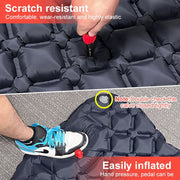 Durable outdoor camping inflatable mattress being inflated with built-in foot pump showing scratch resistant black surface