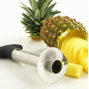 Stainless steel pineapple slicer peeler with black handle and sliced pineapple rings.